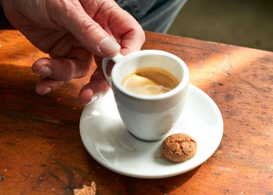 Espresso mit Keks und Hand